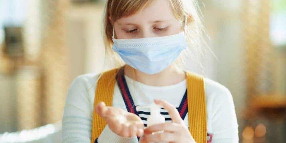 consejos-para-la-buena-proteccion-en-el-aula-de-clases-niña-aplicando-gel-antibacterial-insumosfirstpro.com